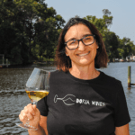 Photo of Cristina Doria standing with a glass of white wine